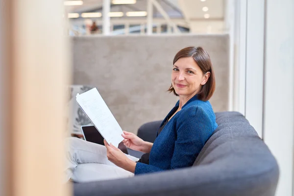 Geschäftsfrau auf Bürocouch mit Papierkram — Stockfoto