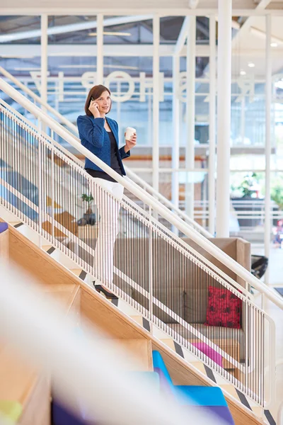 Empresária em pé nas escadas no espaço de escritório brilhante — Fotografia de Stock