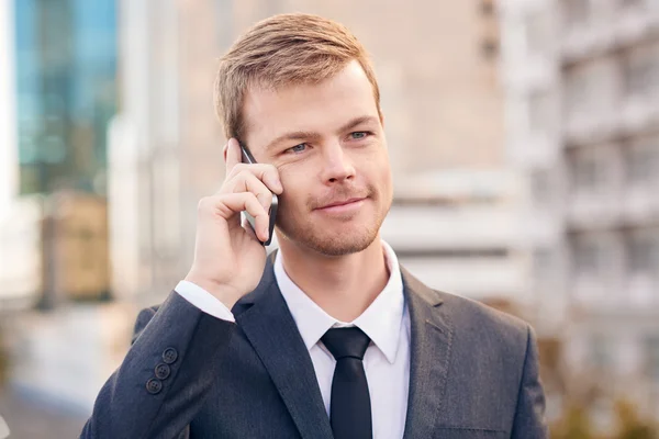 Businessman talking on cellphone in city — Stock Photo, Image