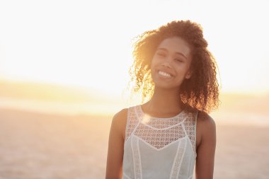 Gün batımında sahilde duran kadın.