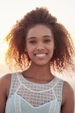 Gün batımında sahilde duran kadın.