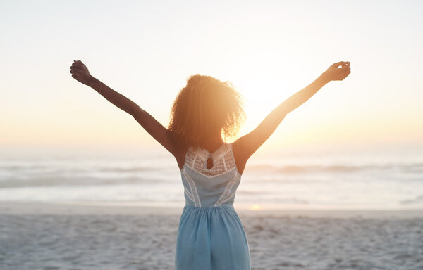 woman standing on beach with arms raised