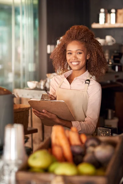 Woman writing on clipboard in cafe — Stock Photo, Image