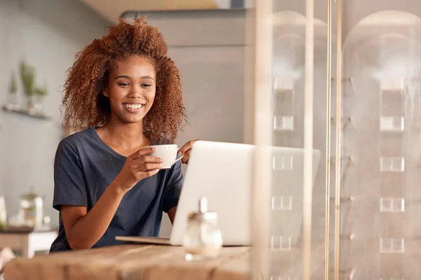 Kadın dizüstü bilgisayarda çalışıyor ve kahve içiyor. — Stok fotoğraf