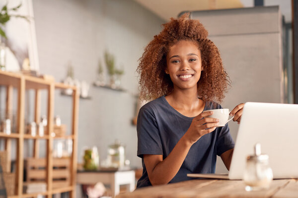 Женщина работает на ноутбуке и пьет кофе
