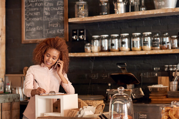 woman talking on phone while working in cafe