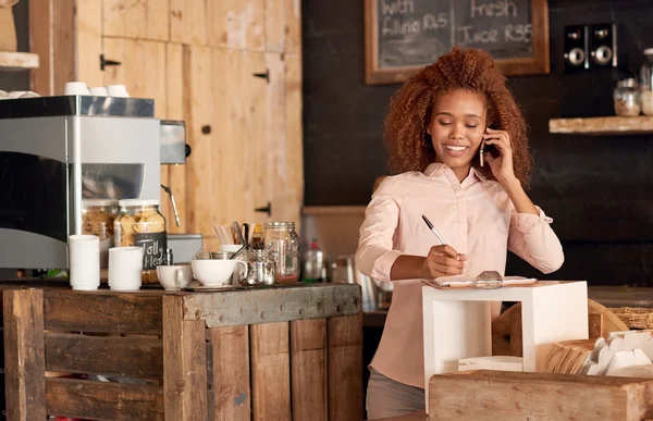 Mujer hablando por teléfono mientras trabaja en la cafetería — Foto de Stock