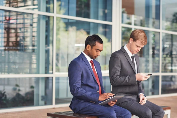 Hombres de negocios sentados y usando tableta y teléfono celular —  Fotos de Stock