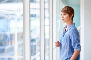 woman looking through large window in corridor