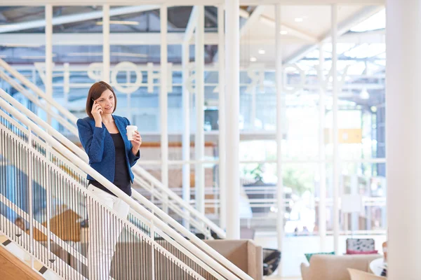 Donna d'affari su scale in ufficio moderno con telefono — Foto Stock