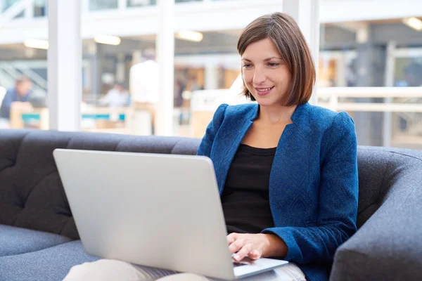 Empresária no sofá no escritório com laptop — Fotografia de Stock