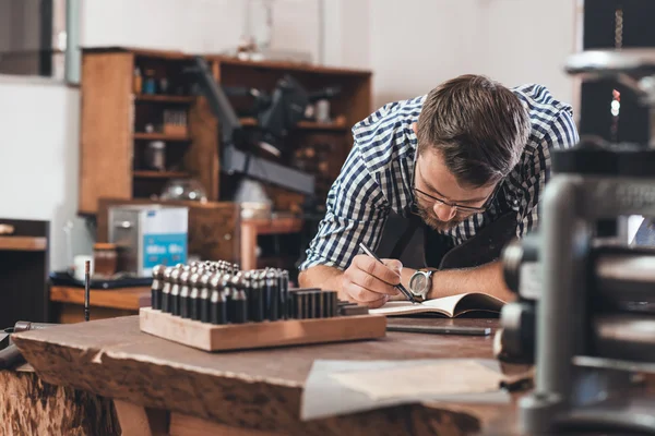 Jeweler sketching out jewelry designs in notebook — Stock Photo, Image