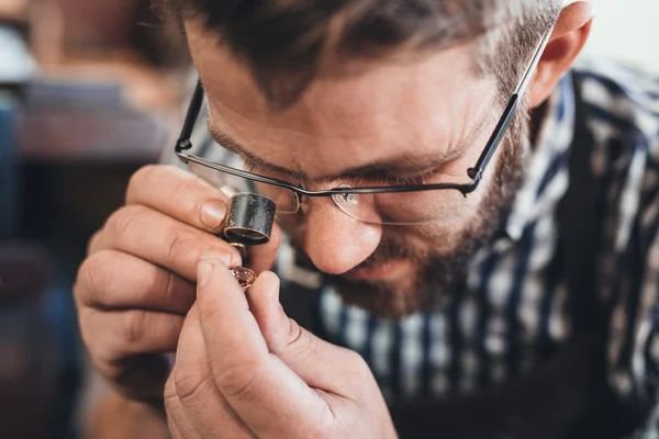 Juwelier untersucht Schmuckstück mit Lupe — Stockfoto