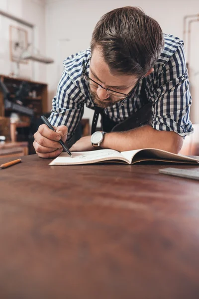 Joalheiro esboçando desenhos de jóias no caderno — Fotografia de Stock