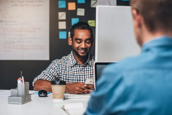 Ontwerper zit aan Bureau mobiele telefoon controleren — Stockfoto