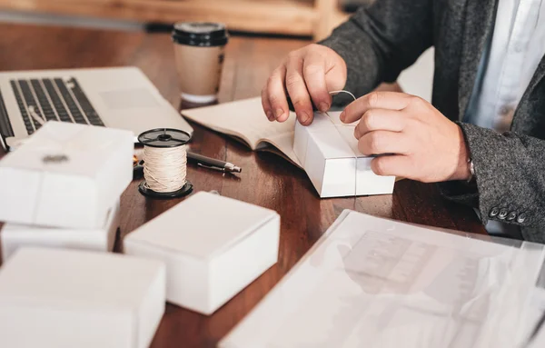 Entrepreneur tying up packages for delivery to customers — Stock Photo, Image