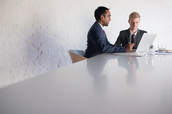 Uomini d'affari in giacca e cravatta parlare insieme sopra il computer portatile — Foto Stock