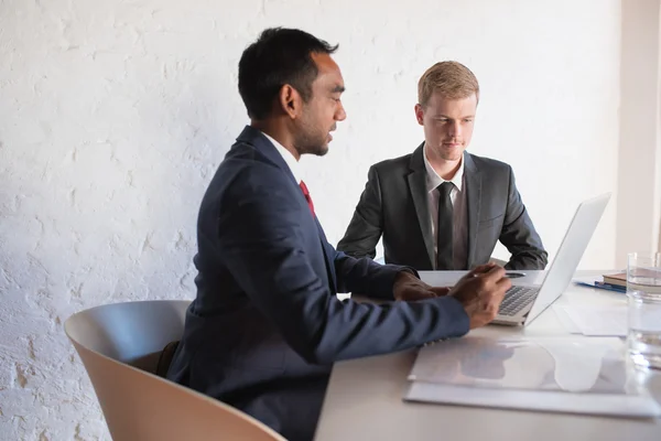 Businessmen in suits talking together over laptop — Stock Photo, Image