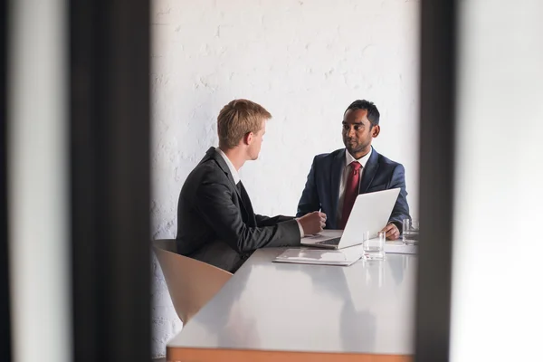 Hommes d'affaires en costumes parlant ensemble sur ordinateur portable — Photo