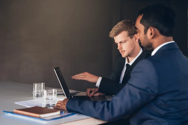 Hommes d'affaires en costumes parlant ensemble sur ordinateur portable — Photo