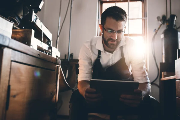 Juwelier met behulp van Tablet PC zittend in werkplaats — Stockfoto