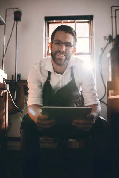 Juwelier met behulp van Tablet PC zittend in werkplaats — Stockfoto