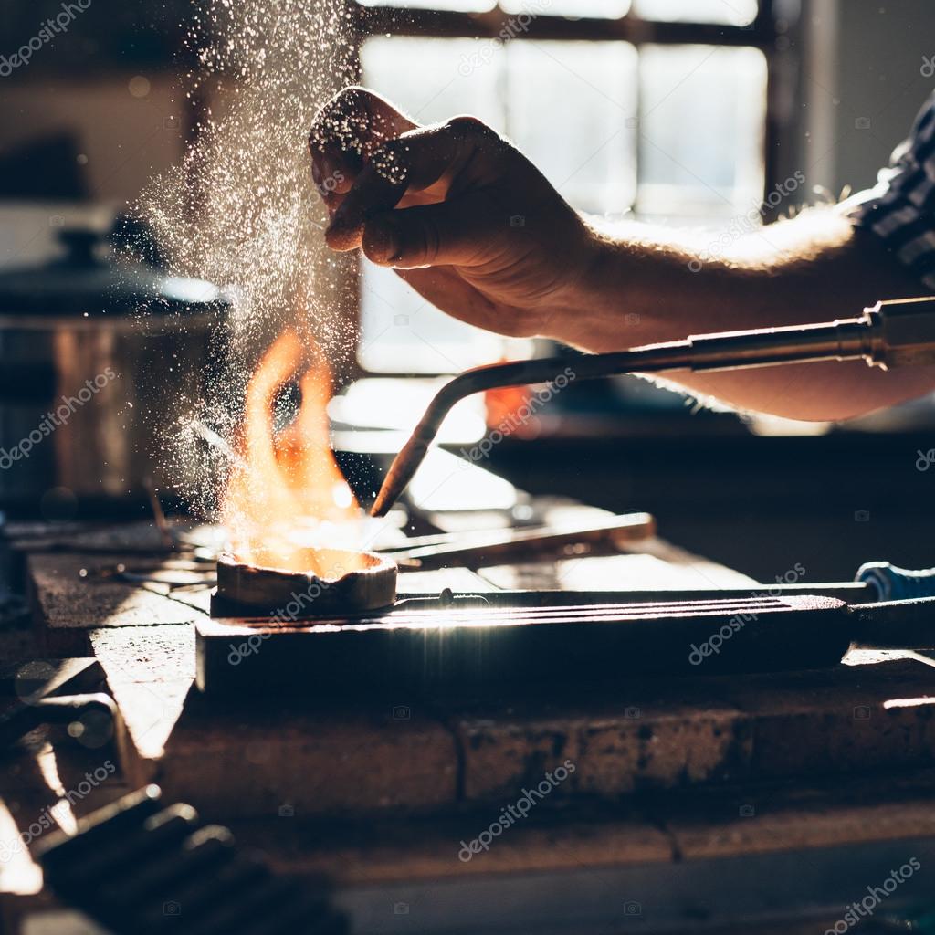 jeweler using torch to melt metal