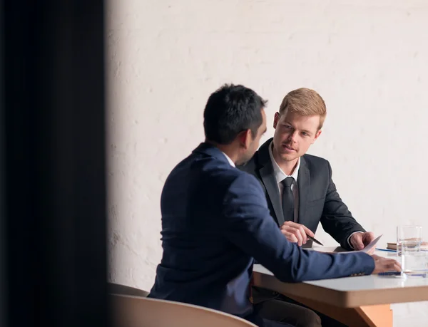 Hombres de negocios en trajes discutiendo documentos juntos — Foto de Stock