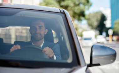 Genç adam, sabah işe gidip gelirken arabasıyla giderken gülümsüyor.