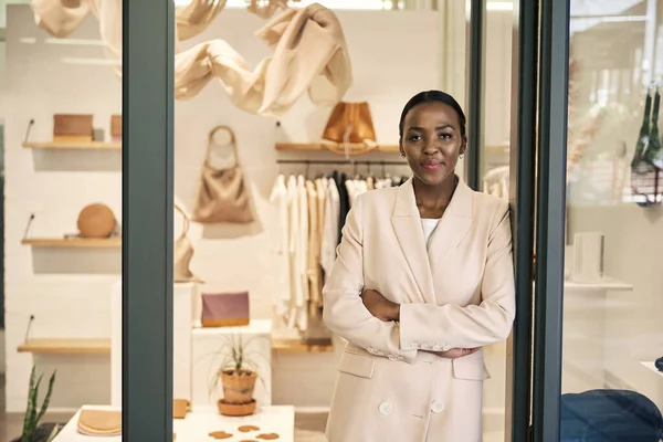 自信に満ちたアフリカ系アメリカ人女性起業家の肖像画彼女の腕で傾いて彼女の店のドアに対して交差 — ストック写真