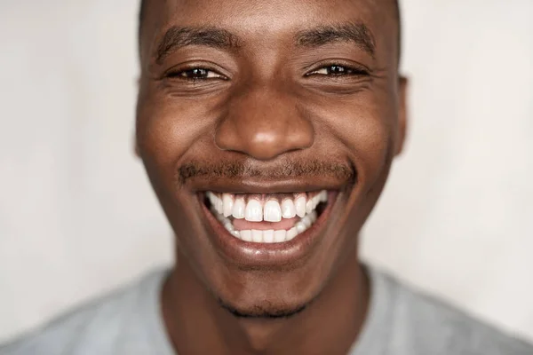 一个穿着T恤衫的无忧无虑的非洲年轻人在家里大笑的画像 — 图库照片