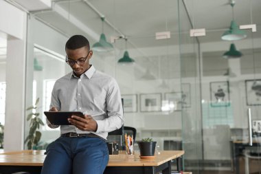 Geniş ve modern bir ofiste dijital tabletle çalışan genç Afrikalı iş adamlarına odaklan.