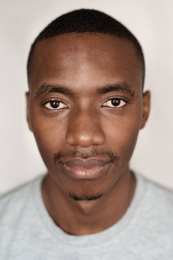 Evde duvarın önünde tişört giyen genç bir Afrikalı 'nın portresi.