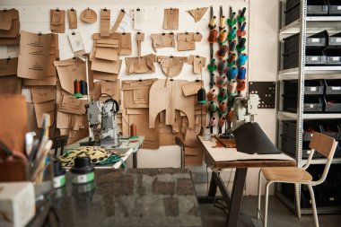 Bir butik deri stüdyosunun içinde dikiş makineleri ve çeşitli alet ve malzemeler var.