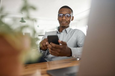 Genç Afrikalı işadamı ofisinde masasında çalışırken cep telefonuna mesaj yolluyor.