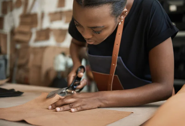 ワークショップでは アフリカの若い女性職人が 革製の片をベンチでカットするためにシアーを使用しました — ストック写真