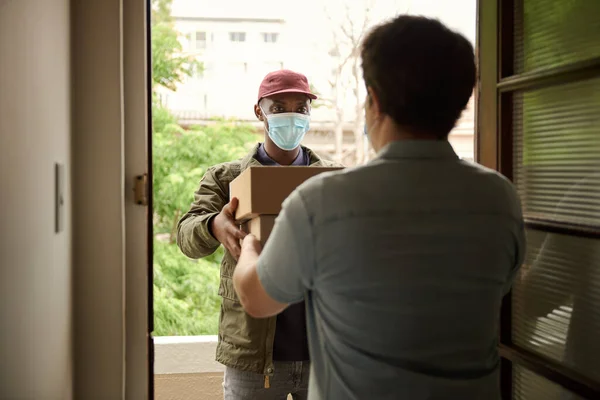 Mensajero Africano Con Una Mascarilla Protectora Entregando Paquetes Cliente Pie —  Fotos de Stock