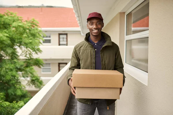 Glimlachende Jonge Afrikaanse Bezorger Buiten Een Appartement Loopbrug Met Pakketten — Stockfoto