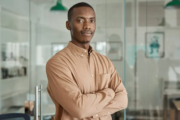 一个自信的年轻非洲商人双臂叉腰站在一间现代化的办公室里的画像 — 图库照片