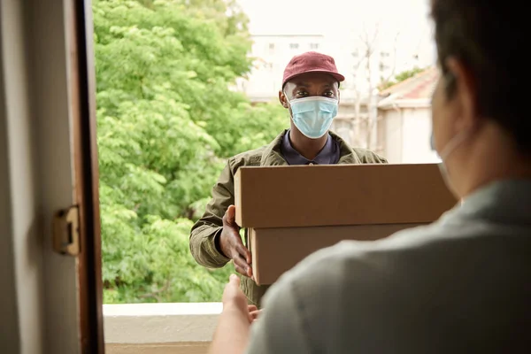 Kurir Afrika Dengan Topeng Wajah Pelindung Memberikan Paket Kepada Pelanggan — Stok Foto