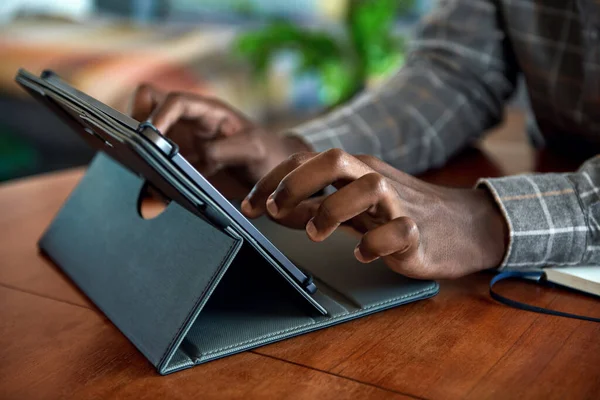 집에서 떨어진 거실의 탁자에서 디지탈 태블릿을 사용하여 일하는 아프리카 사업가의 — 스톡 사진