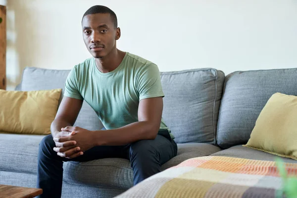 Retrato Jovem Africano Confiante Sentado Sozinho Sofá Sua Sala Estar — Fotografia de Stock