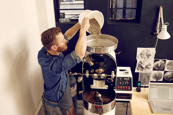 Homem derramando grãos de café na máquina — Fotografia de Stock