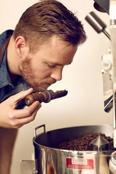 Eigentümer riecht geröstete Kaffeebohnen — Stockfoto