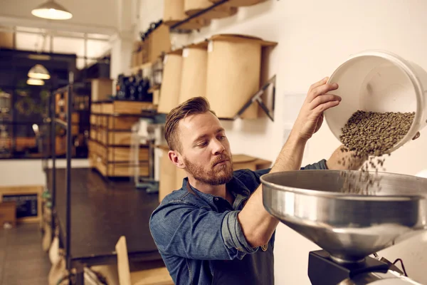 Man häller kaffe bönor i maskin — Stockfoto