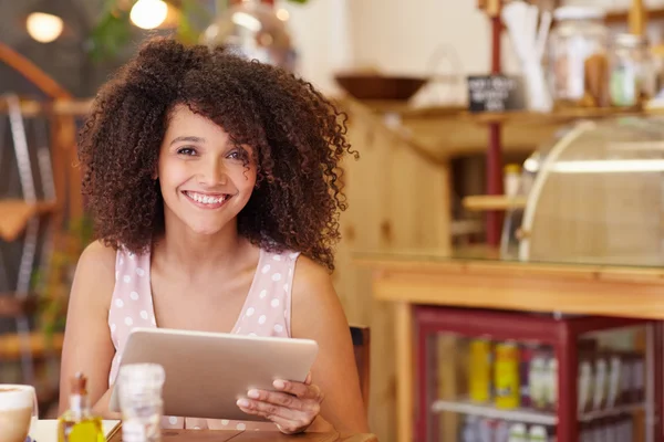 Жінка посміхається і тримає планшет в кафе — стокове фото