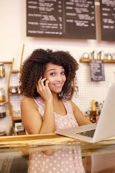 Kvinna att skriva på laptop och prata telefon — Stockfoto