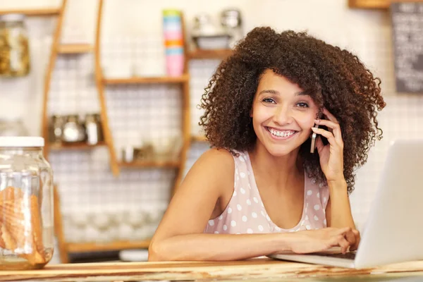 Donna digitando sul computer portatile e parlando al telefono — Foto Stock