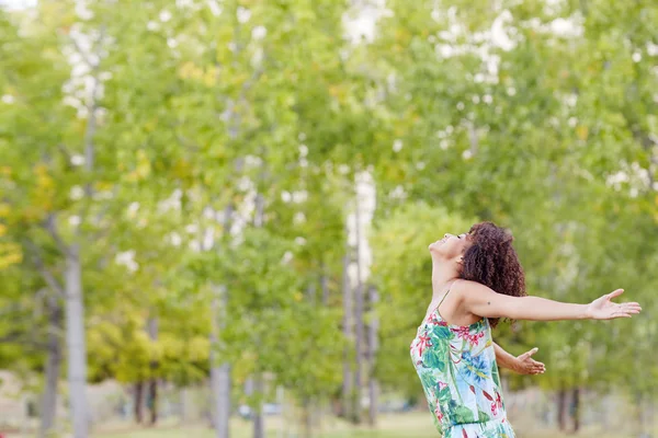 Mulher de pé no parque com braços esticados — Fotografia de Stock