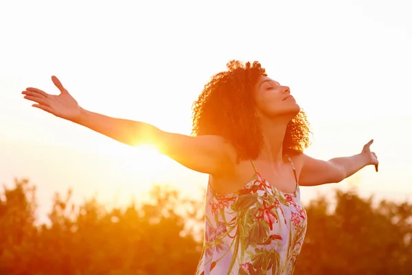 Woman with outstretched arms on summer evening